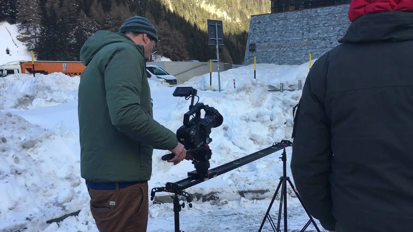 Due operatori con telecamera e slider su un pendio innevato durante le riprese