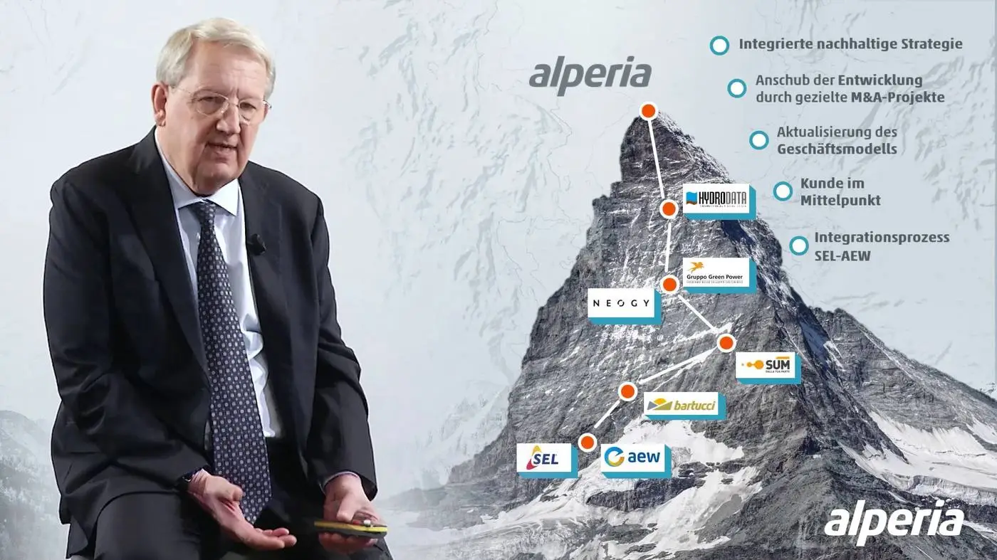 Relatore accanto a una slide con il profilo di una montagna e la mappa del gruppo Alperia