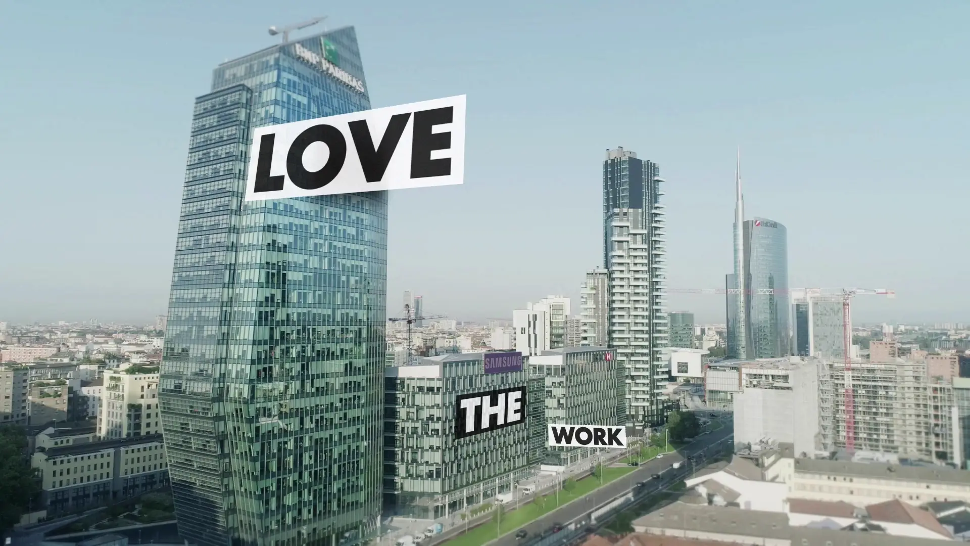 Skyline di Milano con la scritta LOVE THE WORK sovrapposta ai grattacieli