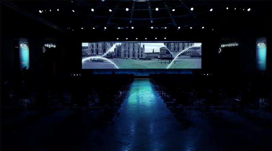 Sala evento in penombra con un ledwall panoramico acceso